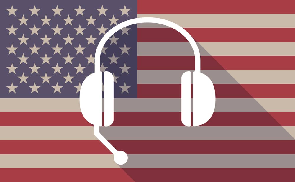 Icono de unos auriculares con micrófono sobre el fondo de la bandera de Estados Unidos, simbolizando la comunicación telefónica en inglés americano.
