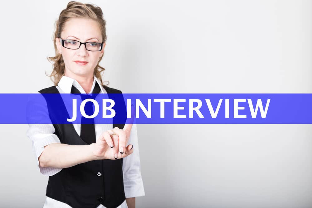 Mujer de negocios presionando un botón virtual que dice "Entrevista de Trabajo". Imagen que representa la preparación para una entrevista laboral.