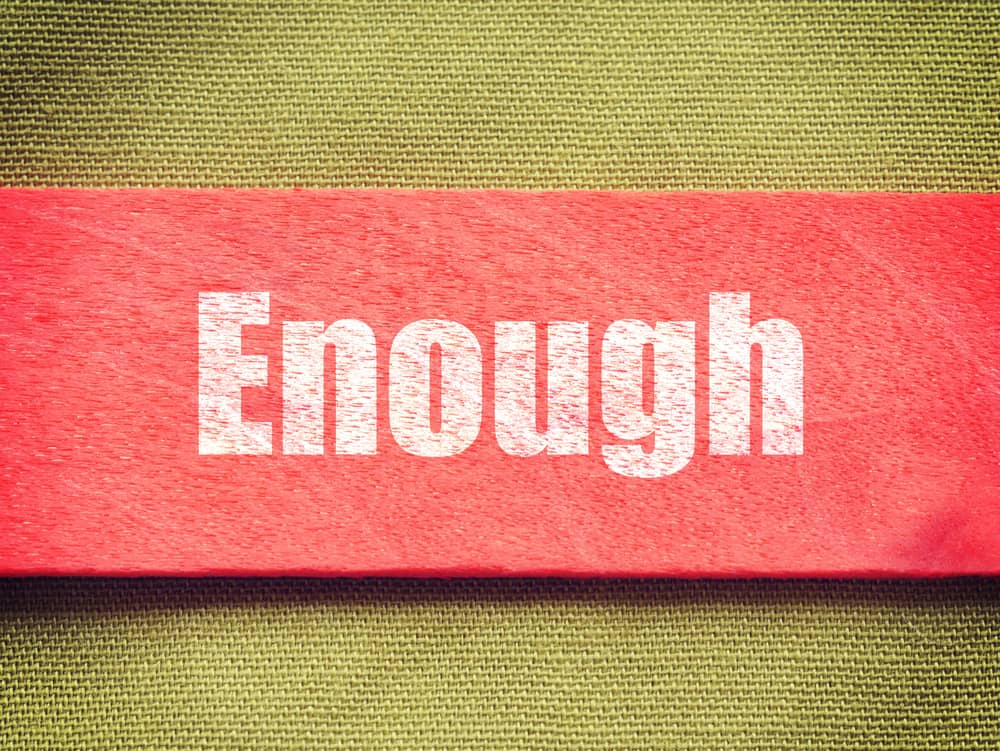La palabra "Enough" en letras blancas sobre un fondo rojo, representando el tema de la suficiencia y sus diferentes usos.